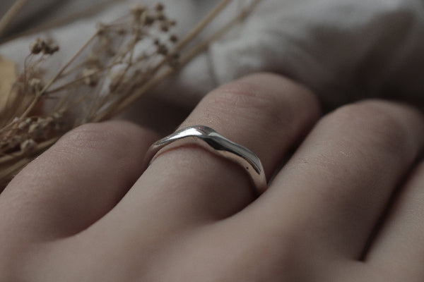 Silver ring on a finger with a blurred background