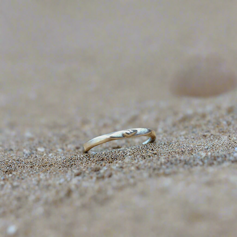 Silver mini signet ring with small raised shell on a sandy surface