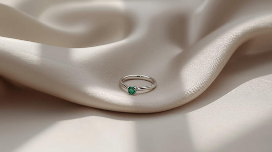 Silver ring with a green gemstone on a soft, beige fabric background